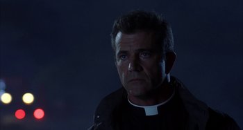 Movie still from “Signs” (2002), directed by M. Night Shyamalan – A man wearing a priest's outfit stares into the distance; Close Up shot, Low angle