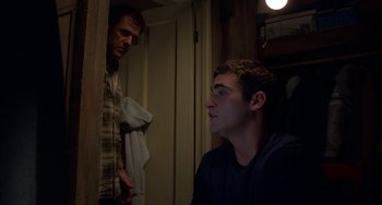 Movie still from “Signs” (2002), directed by M. Night Shyamalan – Two men are standing in a room looking at each other; Medium shot, Low angle