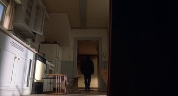 Movie still from “Signs” (2002), directed by M. Night Shyamalan – A person standing in a doorway in a room; Wide shot, Low angle