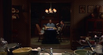 Movie still from “Signs” (2002), directed by M. Night Shyamalan – A group of people sitting at a table in a dark room; Wide shot, High angle