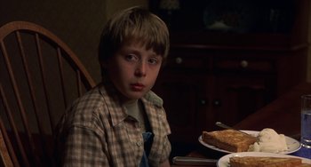 Movie still from “Signs” (2002), directed by M. Night Shyamalan – A boy sitting at a table with a plate of food; Close Up shot, Over the shoulder angle