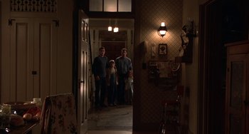 Movie still from “Signs” (2002), directed by M. Night Shyamalan – Three people are standing in a dark hallway; Wide shot, Low angle