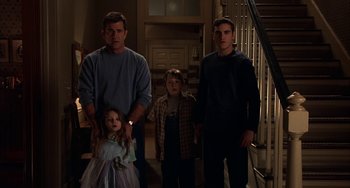 Movie still from “Signs” (2002), directed by M. Night Shyamalan – A man and two young boys standing in front of a staircase; Medium shot, Low angle