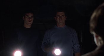 Movie still from “Signs” (2002), directed by M. Night Shyamalan – Two men are holding a flashlight in the dark; Medium shot, Low angle