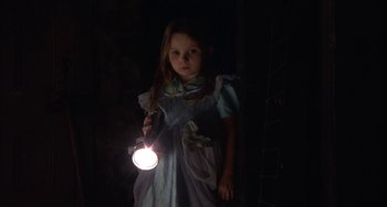 Movie still from “Signs” (2002), directed by M. Night Shyamalan – A little girl holding a flashlight in the dark; Medium shot, Low angle