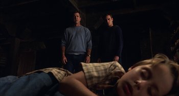 Movie still from “Signs” (2002), directed by M. Night Shyamalan – Two men standing next to each other in a dark room; Medium shot, High angle