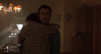 Movie still from “Signs” (2002), directed by M. Night Shyamalan – A man and a boy hugging in a living room; Medium shot, Over the shoulder angle