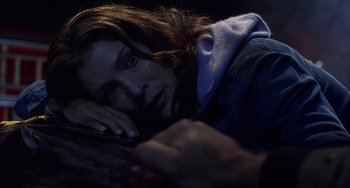 Movie still from “Signs” (2002), directed by M. Night Shyamalan – A woman laying on the ground with her head resting on her hand; Close Up shot, Overhead angle