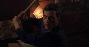 Movie still from “Signs” (2002), directed by M. Night Shyamalan – A young man holding a wooden stick in a dark room; Close Up shot, Over the shoulder angle