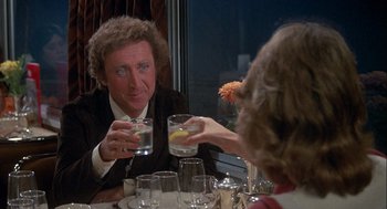 Movie still from “Silver Streak” (1976), directed by Arthur Hiller – A man sitting at a table with a glass of water; Medium shot, Over the shoulder angle