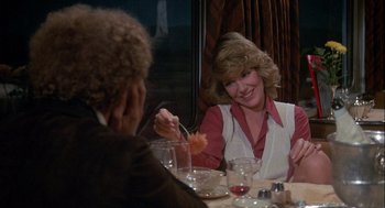 Movie still from “Silver Streak” (1976), directed by Arthur Hiller – A woman sitting at a dinner table with a flower in her hand; Medium shot, Over the shoulder angle