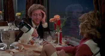 Movie still from “Silver Streak” (1976), directed by Arthur Hiller – Three people sitting at a dinner table with wine glasses; Medium shot, Over the shoulder angle