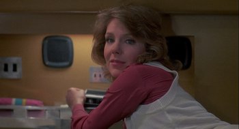Movie still from “Silver Streak” (1976), directed by Arthur Hiller – A woman in a red shirt and a white apron is posing for a picture; Close Up shot, Low angle