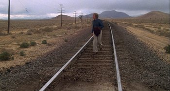 Movie still from “Silver Streak” (1976), directed by Arthur Hiller – A woman is walking along the railroad tracks in the desert; Wide shot, High angle