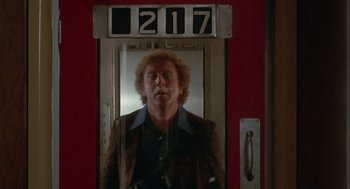 Movie still from “Silver Streak” (1976), directed by Arthur Hiller – A man standing in front of a red door; Medium shot, Low angle
