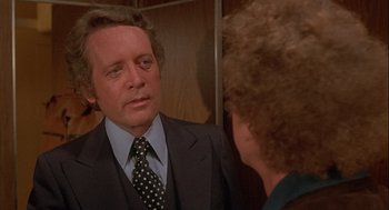 Movie still from “Silver Streak” (1976), directed by Arthur Hiller – A man wearing a suit and tie talking to a woman; Close Up shot, Over the shoulder angle