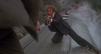 Movie still from “Silver Streak” (1976), directed by Arthur Hiller – A man in a suit and tie holding a gun; Wide shot, Low angle