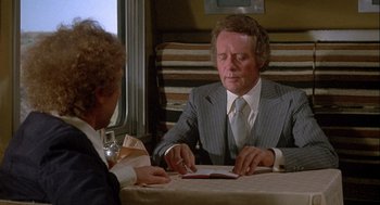 Movie still from “Silver Streak” (1976), directed by Arthur Hiller – Two men sitting at a table in front of each other; Medium shot, Over the shoulder angle