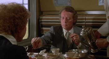 Movie still from “Silver Streak” (1976), directed by Arthur Hiller – A man sitting at a table with a spoon in his hand; Medium shot, Over the shoulder angle