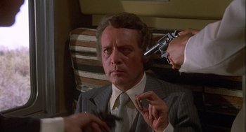 Movie still from “Silver Streak” (1976), directed by Arthur Hiller – A man in a suit and tie holding a gun; Close Up shot, High angle