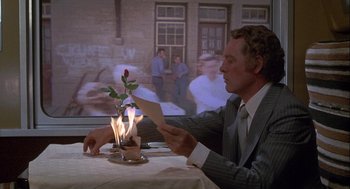 Movie still from “Silver Streak” (1976), directed by Arthur Hiller – A man sitting at a table with a lit candle; Medium shot, Over the shoulder angle