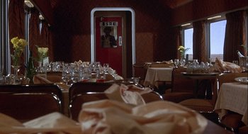 Movie still from “Silver Streak” (1976), directed by Arthur Hiller – A room filled with tables and chairs and a door open; Wide shot, High angle