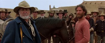 Movie still from “Silverado” (1985), directed by Lawrence Kasdan – A group of men standing next to a brown horse; Medium shot, Over the shoulder angle