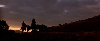 Movie still from “Silverado” (1985), directed by Lawrence Kasdan – A man riding a horse on a field at night; Extreme Wide shot, Low angle