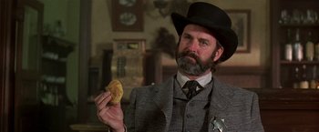 Movie still from “Silverado” (1985), directed by Lawrence Kasdan – A man holding a biscuit in his hand; Close Up shot, Low angle