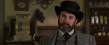 Movie still from “Silverado” (1985), directed by Lawrence Kasdan – A man with a beard wearing a suit and a hat; Close Up shot, Low angle