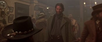 Movie still from “Silverado” (1985), directed by Lawrence Kasdan – A man with a long beard wearing a coat and hat; Medium shot, Over the shoulder angle