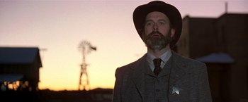Movie still from “Silverado” (1985), directed by Lawrence Kasdan – A man with a beard and a hat in front of a windmill; Close Up shot, Low angle