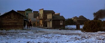 Movie still from “Silverado” (1985), directed by Lawrence Kasdan – A man riding a horse down a street next to buildings; Extreme Wide shot, High angle