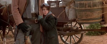 Movie still from “Silverado” (1985), directed by Lawrence Kasdan – A young girl standing next to an old wagon; Medium shot, Over the shoulder angle