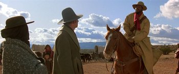 Movie still from “Silverado” (1985), directed by Lawrence Kasdan – A man wearing a hat standing next to a brown horse; Medium shot, Low angle