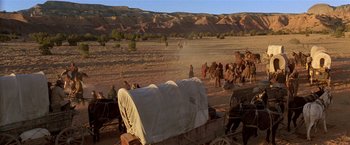 Movie still from “Silverado” (1985), directed by Lawrence Kasdan – A group of people riding on the back of a covered wagon; Extreme Wide shot, High angle