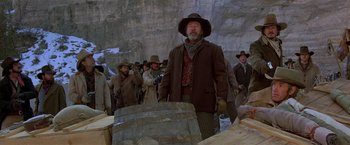 Movie still from “Silverado” (1985), directed by Lawrence Kasdan – A group of men standing next to each other in front of a barrel; Medium shot, Low angle