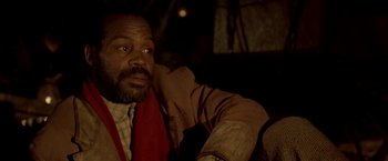 Movie still from “Silverado” (1985), directed by Lawrence Kasdan – A man sitting in a chair with his hand on his shoulder; Close Up shot, Low angle