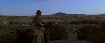 Movie still from “Silverado” (1985), directed by Lawrence Kasdan – A man riding a horse in the middle of the desert; Extreme Wide shot, Low angle