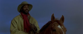 Movie still from “Silverado” (1985), directed by Lawrence Kasdan – A man riding on the back of a brown horse; Close Up shot, Low angle