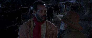 Movie still from “Silverado” (1985), directed by Lawrence Kasdan – A man standing next to a herd of cattle; Close Up shot, Over the shoulder angle