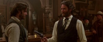 Movie still from “Silverado” (1985), directed by Lawrence Kasdan – A man holding a gun while standing in front of a bar; Medium shot, Low angle