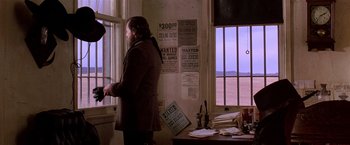 Movie still from “Silverado” (1985), directed by Lawrence Kasdan – A man standing in front of a window in a room; Wide shot, Over the shoulder angle
