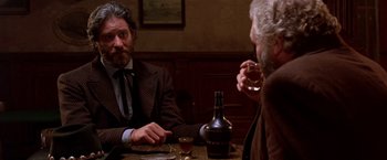 Movie still from “Silverado” (1985), directed by Lawrence Kasdan – Two men sitting at a table with a glass of wine; Close Up shot, Over the shoulder angle