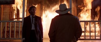 Movie still from “Silverado” (1985), directed by Lawrence Kasdan – Two men in front of a burning building; Medium shot, Over the shoulder angle