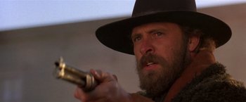 Movie still from “Silverado” (1985), directed by Lawrence Kasdan – A man with a long beard holding a gun in his hand; Close Up shot, Low angle