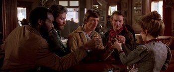 Movie still from “Silverado” (1985), directed by Lawrence Kasdan – A group of men sitting at a table drinking; Medium shot, Low angle
