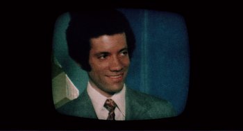 Movie still from “Sisters” (1972), directed by Brian De Palma – A man in a suit and tie smiling for the camera; Close Up shot, High angle