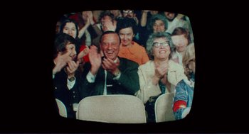 Movie still from “Sisters” (1972), directed by Brian De Palma – An old photo of people clapping in a theater; Medium shot, High angle