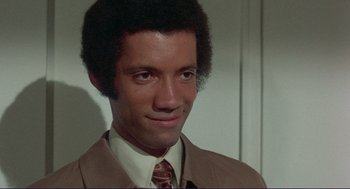 Movie still from “Sisters” (1972), directed by Brian De Palma – A person wearing a suit and tie; Close Up shot, High angle